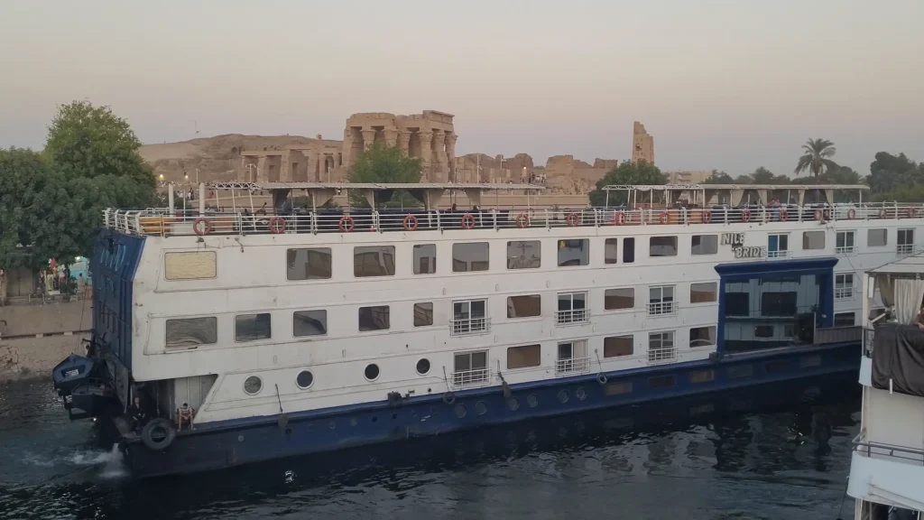 Cruzeiro ancorado no rio Nilo com vista para um dos templos antigos do Egito.