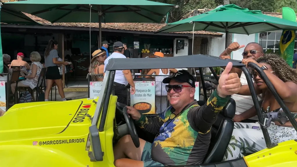 Buggy amarelo com turistas passando por uma das praias de Búzios.