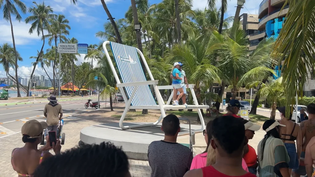 Turistas aguardando para tirar foto na cadeira gigante de Maceió.