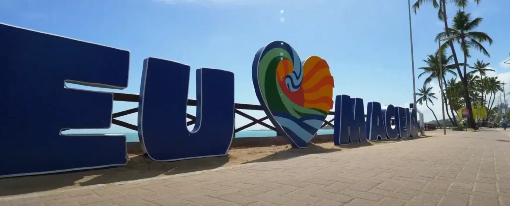 Letreiro com a frase Eu amo Maceió em um dia ensolarado na orla da praia.