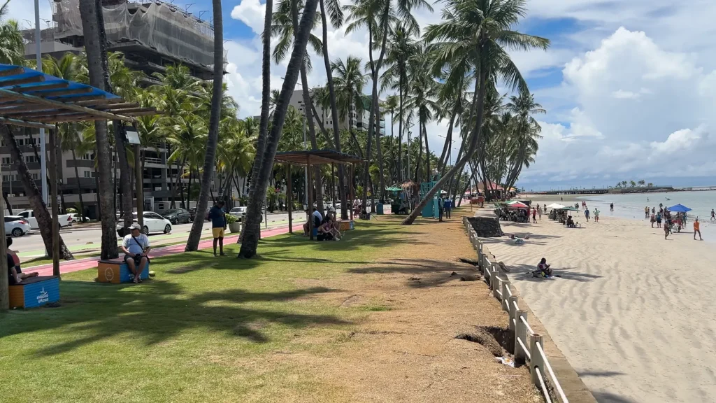 Trecho da orla de uma das praias de Maceió com turistas e ambulantes.
