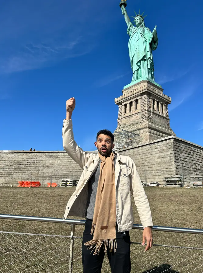 Pessoa em frente à Estátua da Liberdade durante viagem a Nova York.